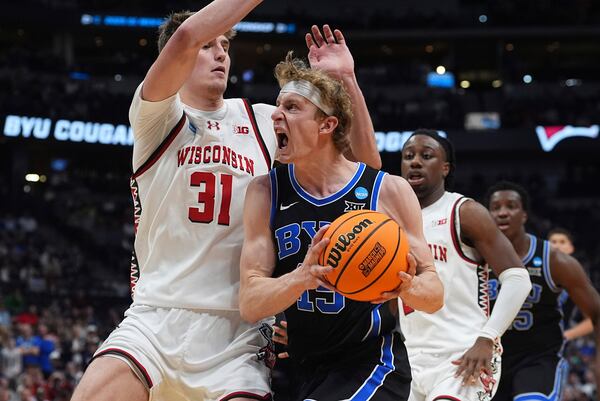 BYU forward Richie Saunders, front right, drives to the basket as Wisconsin forward Nolan Winter (31) defends during the second half in the second round of the NCAA college basketball tournament Saturday, March 22, 2025, in Denver. (AP Photo/David Zalubowski)