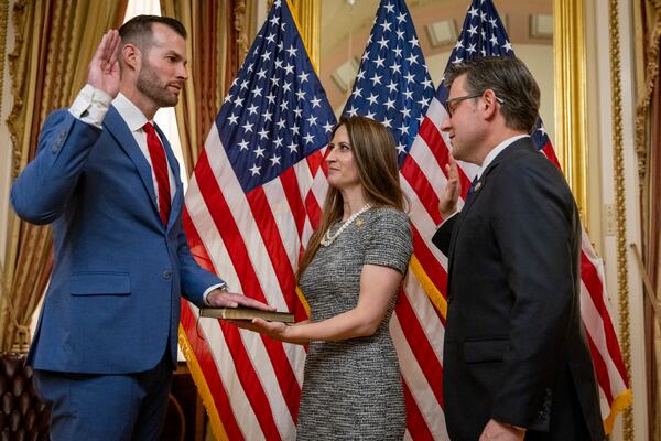 Speaker of the House Mike Johnson (right) administers the oath of office to U.S. Rep. Clay Fuller during a ceremonial swearing-in on Capitol Hill in Washington. Fuller's wife, Kate, holds the Bible. (Nathan Posner for the AJC)