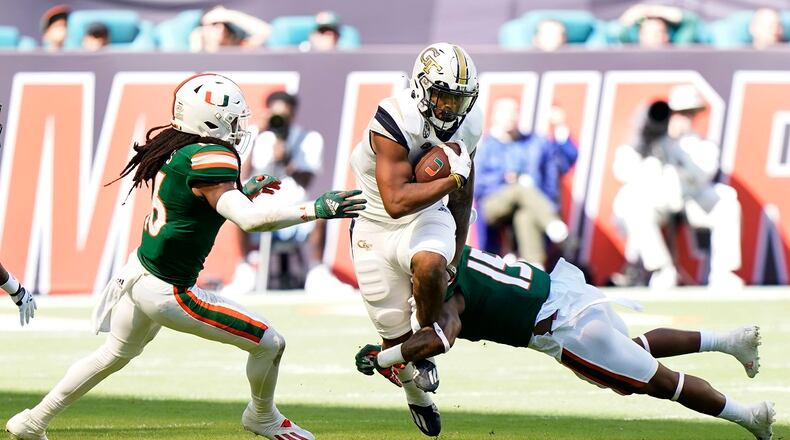 Miami cornerback Malik Curtis, left, and safety Avantae Williams, right, tackle Georgia Tech wide receiver Azende Rey during the first half of an NCAA college football game, Saturday, Nov. 6, 2021, in Miami Gardens, Fla. (AP Photo/Wilfredo Lee)