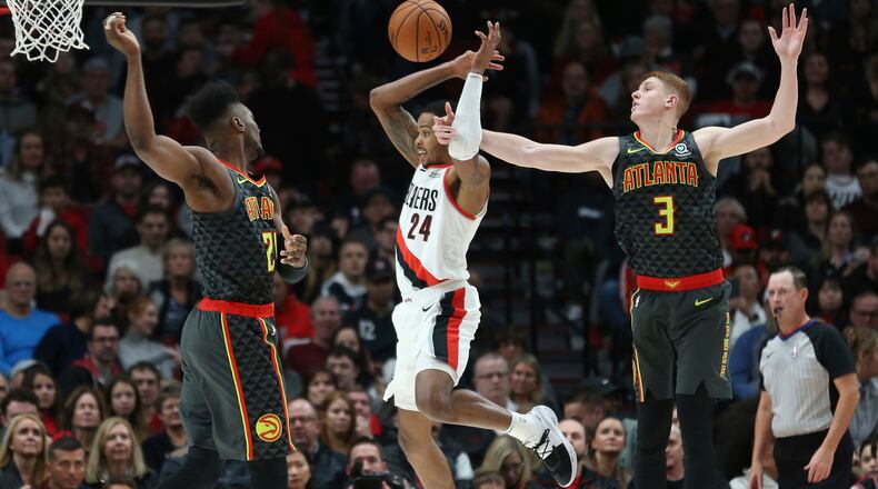Portland Trail Blazers guard Kent Bazemore (center) is fouled by Atlanta Hawks guard Kevin Huerter (right) as forward Bruno Fernando defends during the first half Sunday, Nov. 10, 2019, in Portland, Ore.