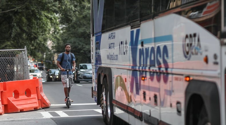 A man rides an electric scooter Wednesday while sharing a lane with a bus on West Peachtree Street in Atlanta near where another scooter rider was killed. Mayor Keisha Lance Bottoms issued an executive order Thursday to prohibit additional scooters while the city tries to determine how to handle them. The order does not apply to existing permits for 13,750 scooters. BRANDEN CAMP/SPECIAL