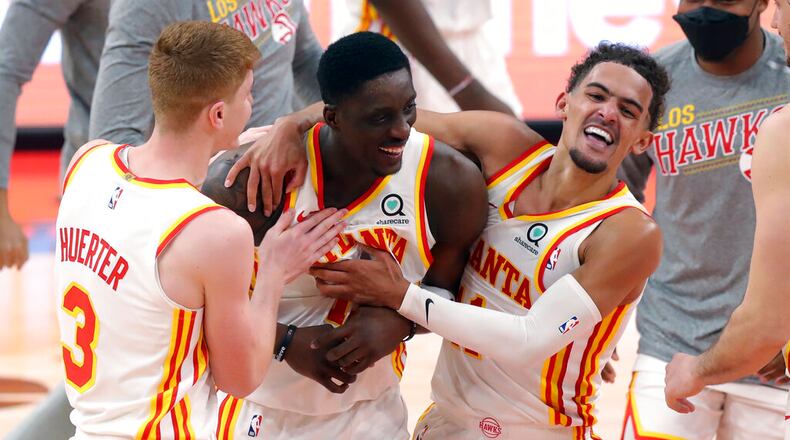 Atlanta Hawks' Tony Snell, center, is congratulated by Kevin Huerter (3) and Trae Young after his basket at the buzzer that gave the team a 121-120 win over the Toronto Raptors in an NBA basketball game Thursday, March 11, 2021, in Tampa, Fla. (AP Photo/Mike Carlson)