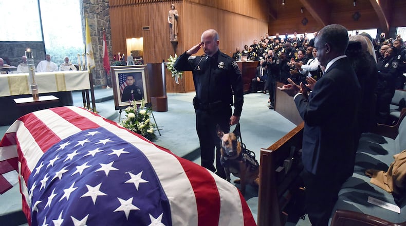 December 18, 2018 Dunwoody - K9 Officer Indi, who was shot, is brought to the casket of officer Edgar Isidro Flores during his funeral service at All Saints Catholic Church in Dunwoody on Tuesday, December 18, 2018. Flores was shot and killed in DeKalb County in the line of duty last week. HYOSUB SHIN / HSHIN@AJC.COM