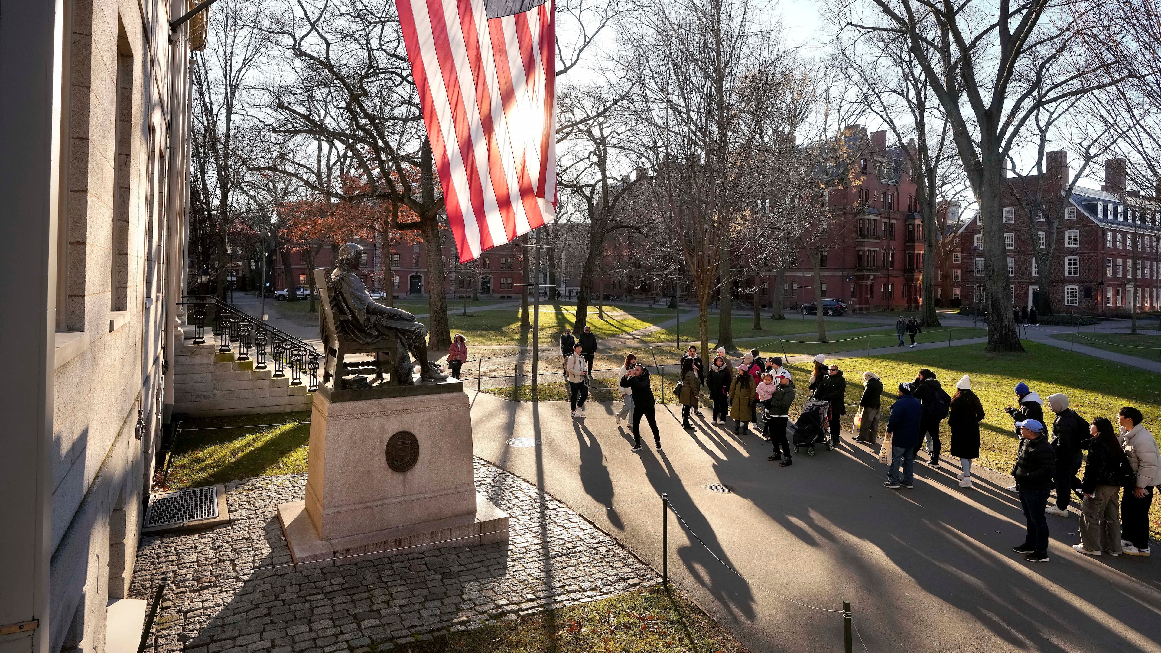 FILE - People take photos near a John Harvard statue, left, on the Harvard University campus, Jan. 2, 2024, in Cambridge, Mass. (AP Photo/Steven Senne, File)