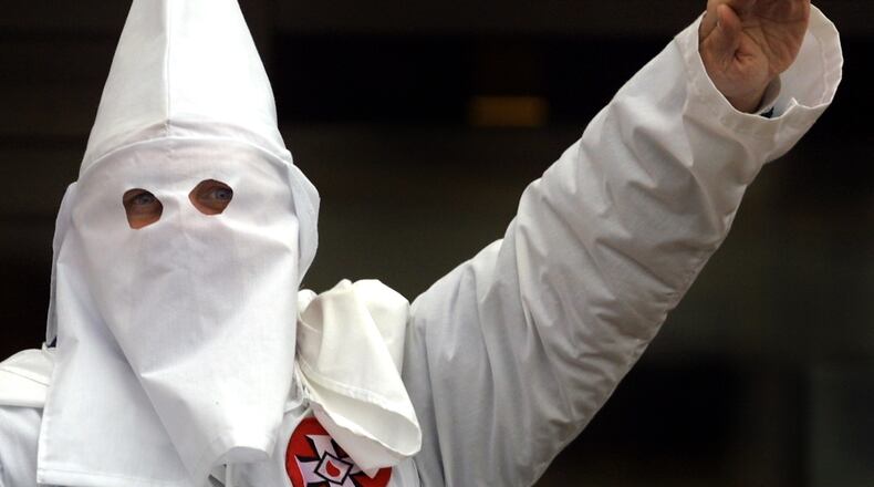 A Klansman raises his left arm during a 'white power' chant at a Ku Klux Klan rally December 16, 2000 in Skokie, IL. A Wisconsin chapter of the Ku Klux Klan held a 'White Pride Rally' on the steps of the Cook County Courthouse located in Skokie, a suburb northwest of Chicago.