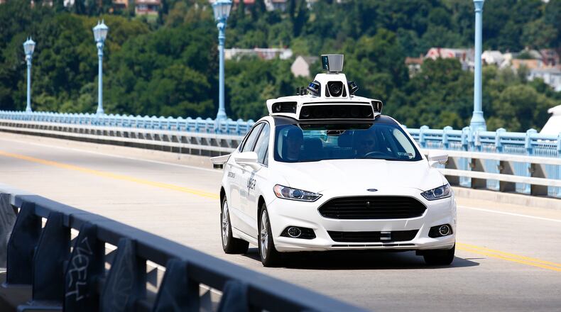 In this Thursday, Aug. 18, 2016, photo, Uber employees test a self-driving Ford Fusion hybrid car, in Pittsburgh.