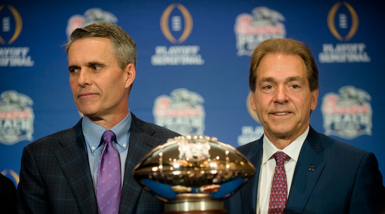 Washington coach Chris Petersen, left, and Alabama coach Nick Saban stand with the Chick-fil-A Peach Bowl trophy during a news conference Friday, Dec. 30, 2016, in Atlanta. (Albert Cesare/The Montgomery Advertiser via AP)