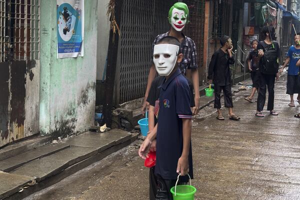 Children wearing face masks wait to throw water during the first day of annual traditional water festival also known as "Thingyan", in Yangon, Myanmar, Sunday, April 13, 2025. (AP Photo/Thein Zaw)