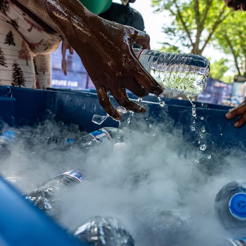 A vendor pulls out a bottle of water from a tank using dry ice to keep it cold, during a heat wave at the Great American State Fair on the National Mall, Thursday, July 2, 2026, in Washington. (AP Photo/Alex Brandon)