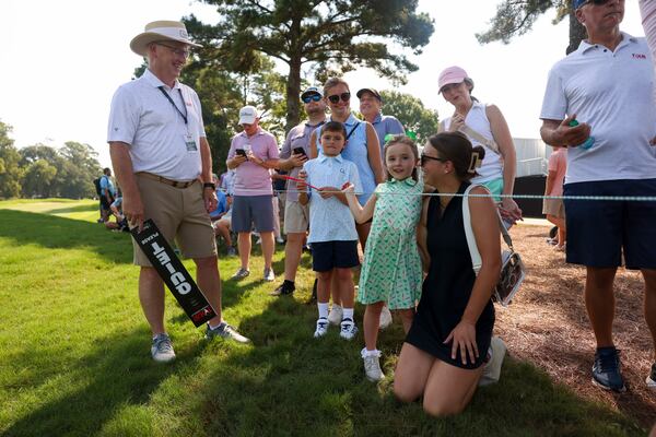 Gallery manager David McCollum (left) talks with golf fans Oaken Wilmot, 6 (center) and her aunt Claire Verbosky, of Johns Creek (kneeling right) as they wait for golfers on the first fairway during the second round of the Tour Championship at East Lake Golf Club, on Friday, Aug. 28, 2026, in Atlanta. (Jason Getz/AJC)