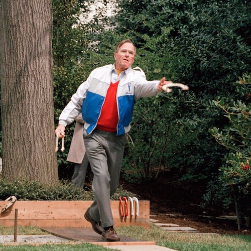 FILE - President George H.W. Bush lets loose of a horseshoe during the dedication of the new horseshoe pit on the White House lawn Saturday April 1, 1989, in Washington. (AP Photo/Barry Thumma)