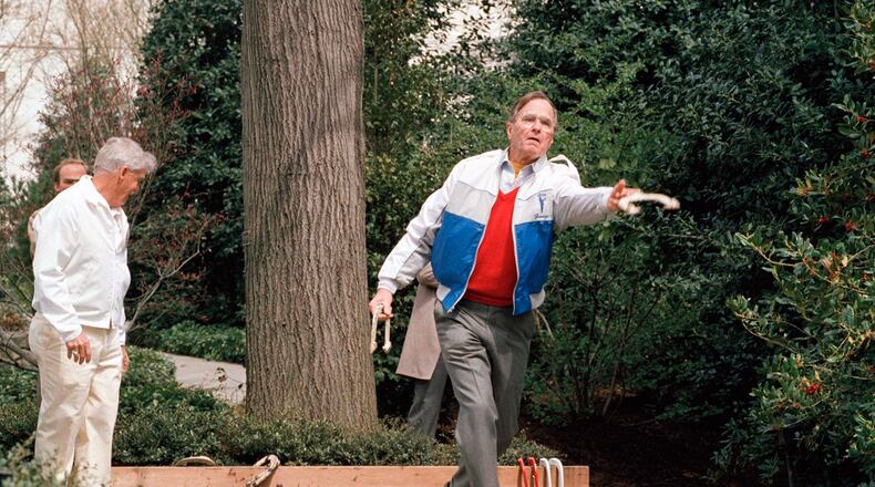 FILE - President George H.W. Bush lets loose of a horseshoe during the dedication of the new horseshoe pit on the White House lawn Saturday April 1, 1989, in Washington. (AP Photo/Barry Thumma)