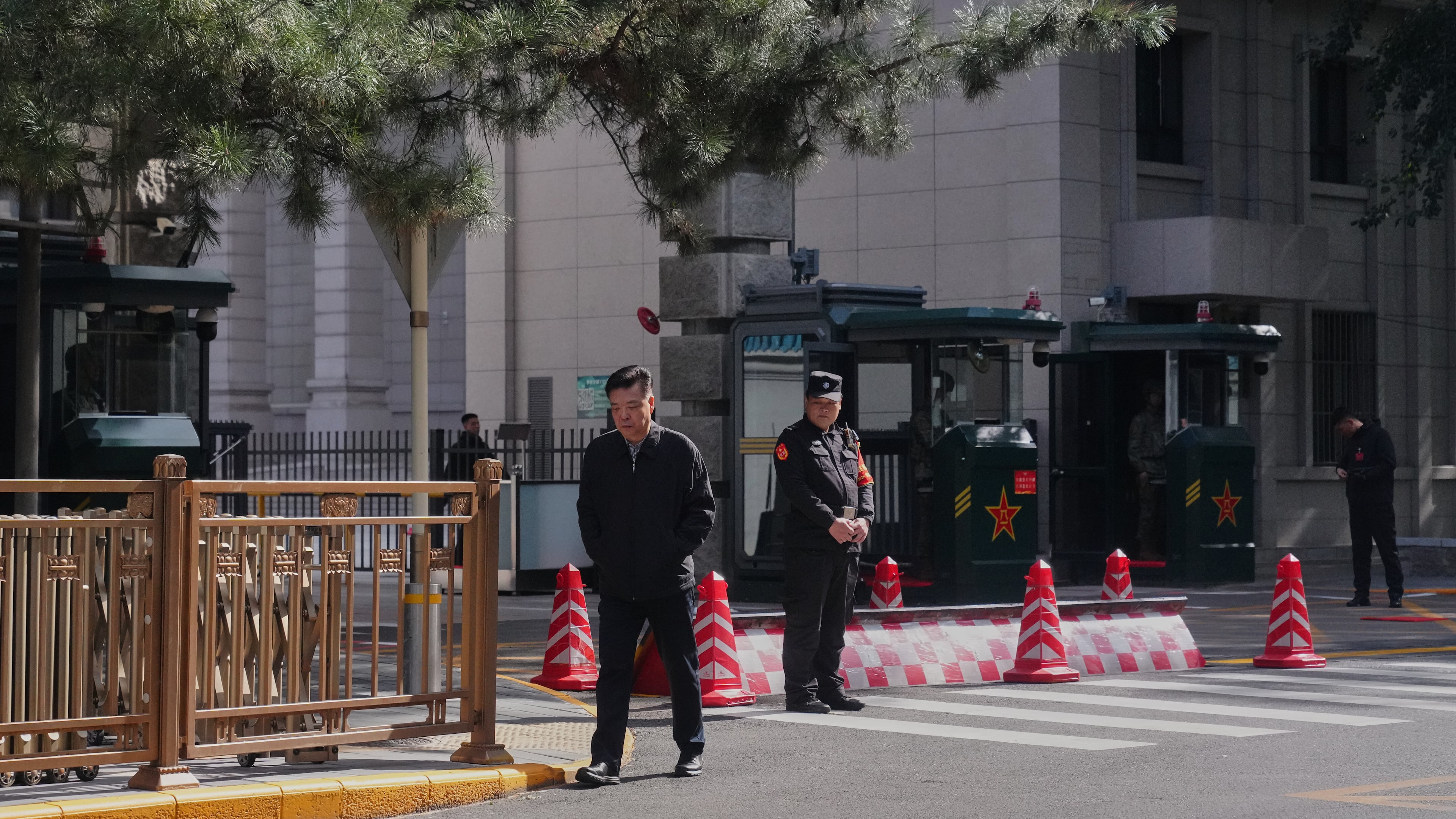 A man walks by Chinese security personnel guarding the entrance to the Jingxi Hotel where the Communist Party's Central Committee is holding its fourth plenum, in Beijing, Monday, Oct. 20, 2025. (AP Photo/Andy Wong)