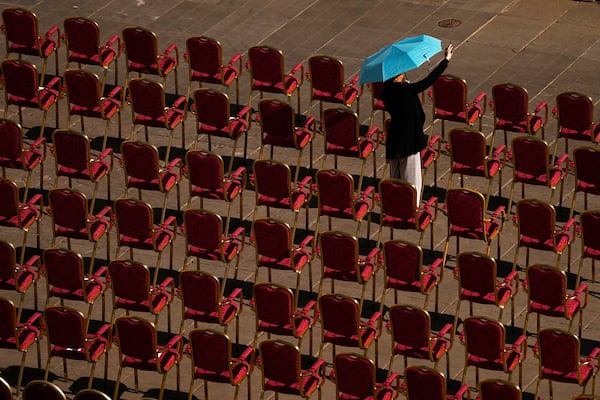 A woman takes pictures ahead of a mass presided over by Vatican Secretary of State, Cardinal Pietro Parolin on the second of nine days of mourning for late Pope Francis in St. Peter's Square, at the Vatican, Sunday, April 27, 2025. (AP Photo/Andreea Alexandru)