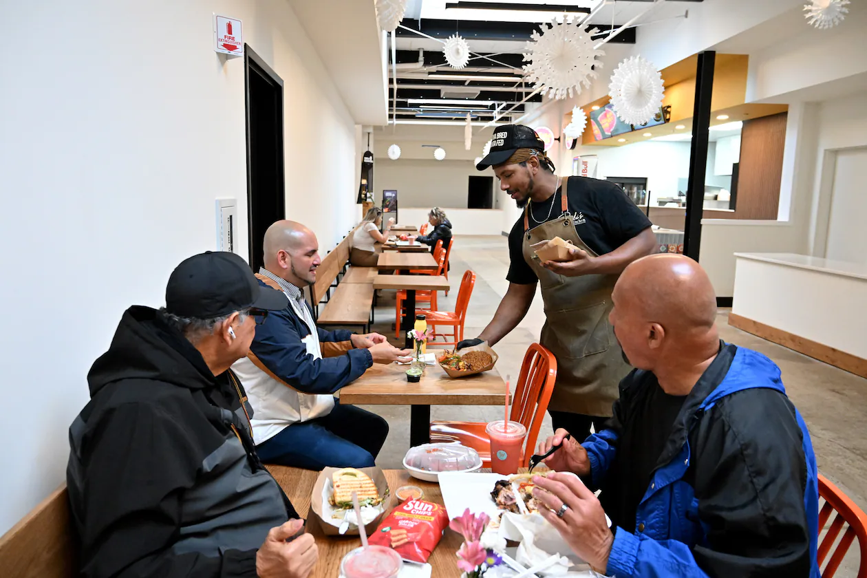 Ali Lemma (standing), owner and chef at Ruki’s Kitchen, serves food at Terminal South, Thursday, Feb. 26, 2026, in Atlanta. This is Lemma's first year participating in Atlanta's Black Restaurant Week. (Hyosub Shin/AJC)