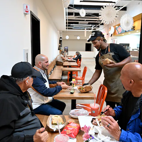 Ali Lemma (standing), owner and chef at Ruki’s Kitchen, serves food at Terminal South, Thursday, Feb. 26, 2026, in Atlanta. This is Lemma's first year participating in Atlanta's Black Restaurant Week. (Hyosub Shin/AJC)