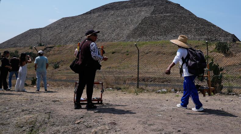 Handicraft vendors and tourists stand outside the Teotihuacan pyramids, which remained closed a day after a gunman opened fire on tourists at the archaeological site on the outskirts of Mexico City, Tuesday, April 21, 2026. (AP Photo/Marco Ugarte)