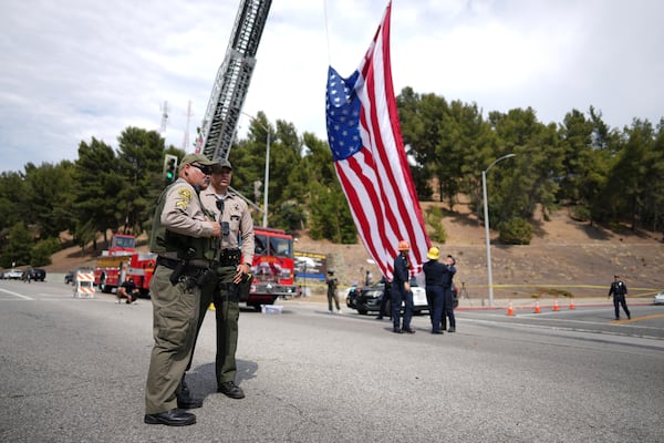 Sheriff's deputies stand along a procession route near where an explosion at a training facility killed three deputies on Friday, July 18, 2025, in Los Angeles. (AP Photo/Eric Thayer)