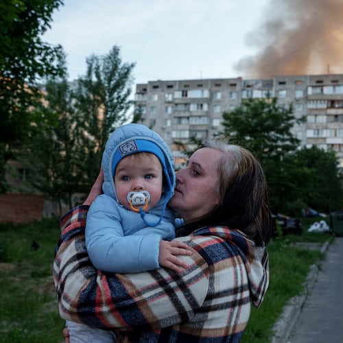 A woman carries a baby near a residential house damaged after a Russian strike in Kyiv, Ukraine, on Tuesday, June 2, 2026. (AP Photo/Evgeniy Maloletka)