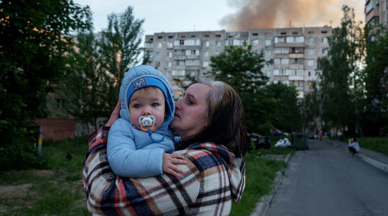 A woman carries a baby near a residential house damaged after a Russian strike in Kyiv, Ukraine, on Tuesday, June 2, 2026. (AP Photo/Evgeniy Maloletka)