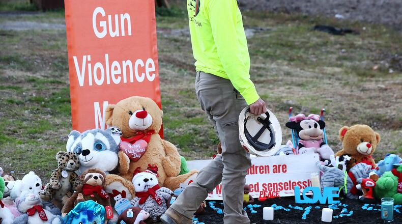 Former firefighter Gage Scarborough, who declined to have his face photographed, visits the growing memorial for 6-month-old Grayson Fleming-Gray outside the Food Mart where the child was shot and killed Jan. 24. (Curtis Compton / Curtis.Compton@ajc.com)