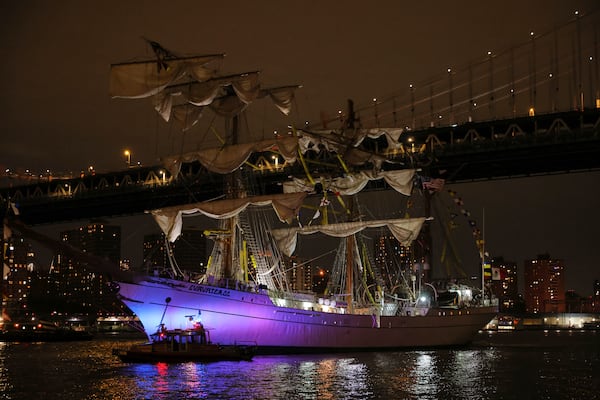 A New York Police Department harbor unit passes in front of the Cuauhtémoc, a masted Mexican Navy training ship as it sits stranded near the Manhattan Bridge after colliding with the Brooklyn Bridge, Saturday, May 17, 2025, in New York. (AP Photo/Yuki Iwamura)
