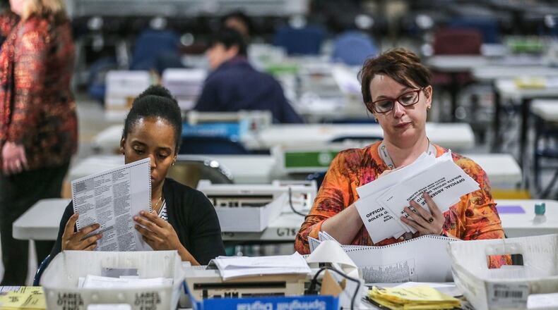 Elections Coordinator, Shantell Black (left) and Elections Deputy Director, Kristi Royston open and scan absentee ballots on Wednesday morning, Nov. 7, 2018 at the Gwinnett County Voter Registration and Elections Office in Lawrenceville. JOHN SPINK/JSPINK@AJC.COM