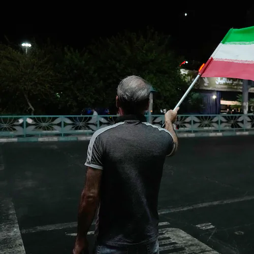 A pro-government demonstrator waves an Iranian flag in a gathering commemorating the late Iranian Supreme Leader Ayatollah Ali Khamenei at a square in Tehran, Iran, Saturday, July 11, 2026. (AP Photo/Vahid Salemi)