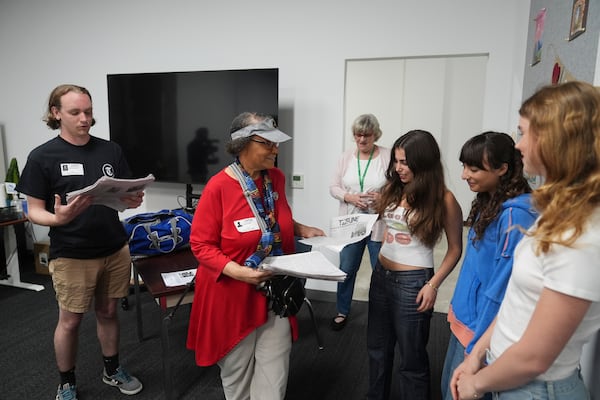 Claire Smith, founding executive director of Temple University's sports media center, center, and Samuel O'Neal, left, editor-in-chief of the Temple News, deliver copies of the Palisades High School newspaper to staff, Wednesday, May 14, 2025, in Santa Monica, Calif. (AP Photo/Marcio Jose Sanchez)