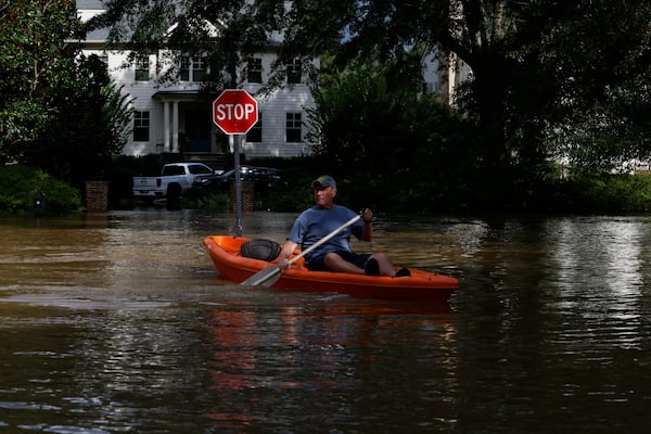 Charlie Bradley uses his kayak to cross flooded  Cochise Road in Vinings following a night of heavy rain from Hurricane Helene in September 2024. (Miguel Martinez/AJC 2024)