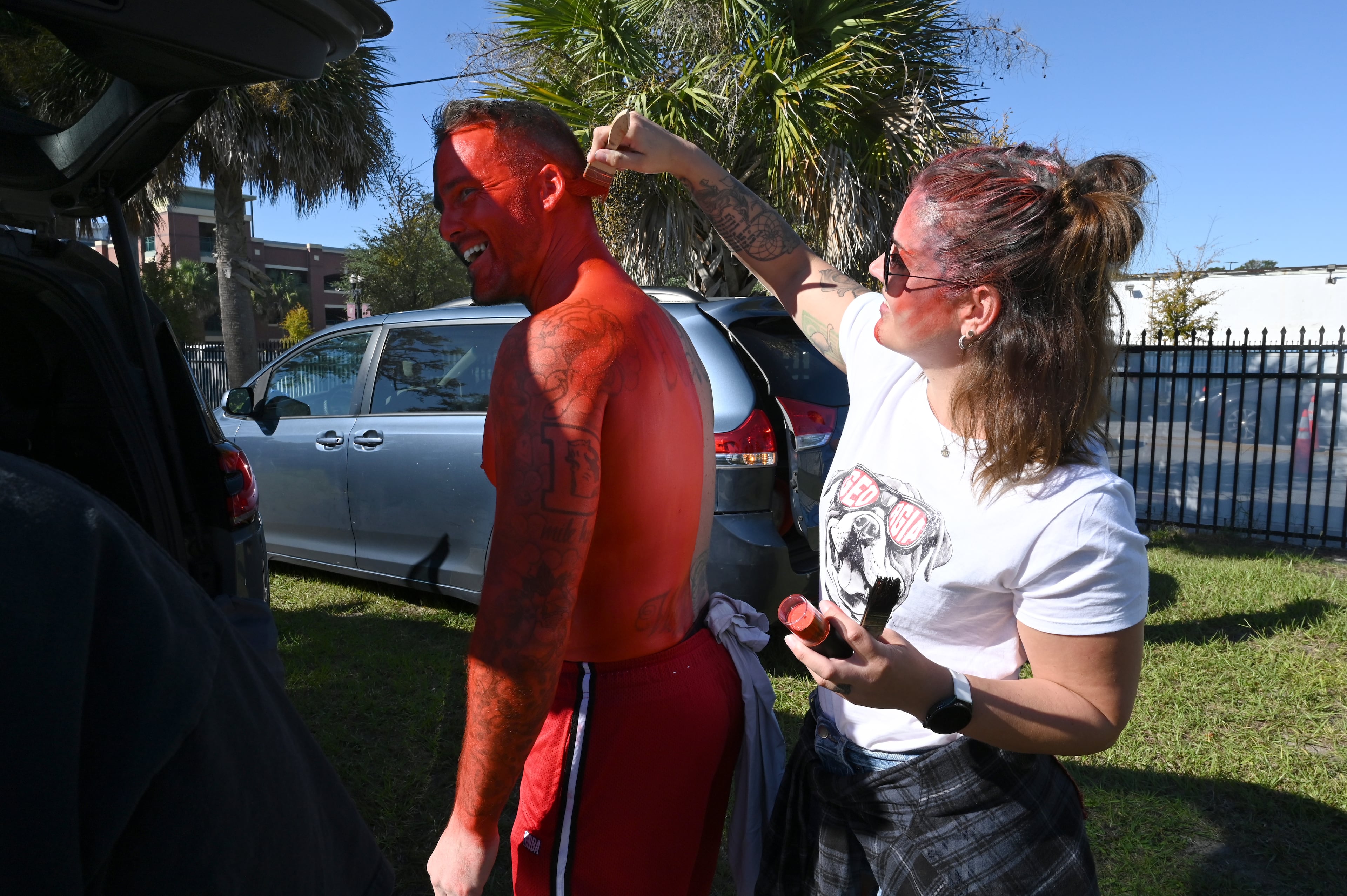 Georgia fan Steve Couch gets painted by his wife Christina outside EverBank Stadium prior to an NCAA football game between Georgia and Florida, Saturday, Nov. 1, 2025, Jacksonville, Fla. (Hyosub Shin / AJC)
