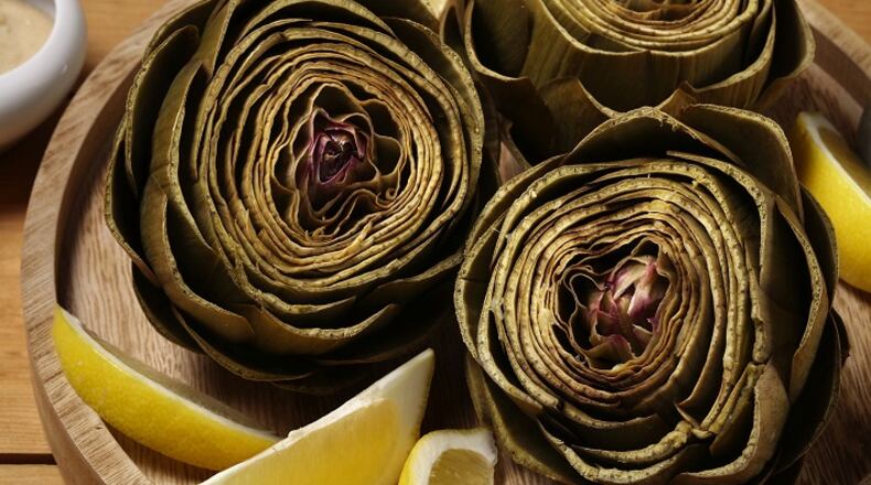 Artichokes steam in a lemon-, garlic- and bay leaf-scented bath until tender. A tahini dip for dunking brings more lemon and garlic to the dish. (E. Jason Wambsgans/Chicago Tribune/TNS)
