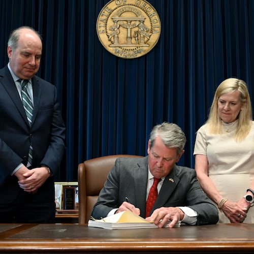 Gov. Brian Kemp (center) signs the state's new budget alongside Rick Dunn (left), director of the Governor's Office of Planning and Budget, and first lady Marty Kemp. (Hyosub Shin/AJC)