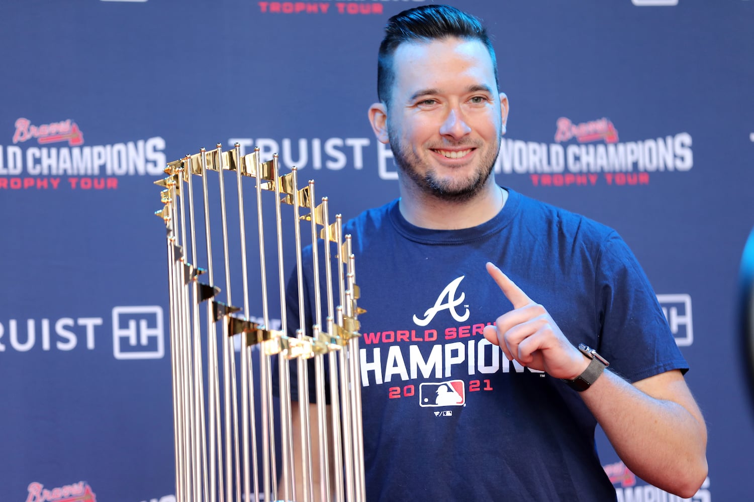 Joey Hnath poses beside the 2021 World Champions Trophy. Miguel Martinez for The Atlanta Journal-Constitution 