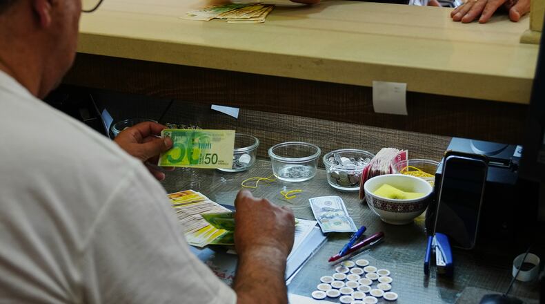 A currency exchange employee counts Israeli Shekels at a bureau in the West Bank city of Bethlehem, Tuesday, July 7, 2026. (AP Photo/Mahmoud Illean)