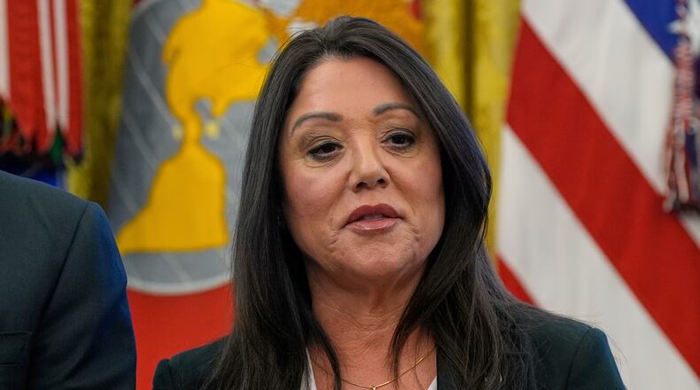 FILE - Labor Secretary Lori Chavez-DeRemer listens as President Donald Trump speaks with reporters while signing executive orders in the Oval Office of the White House, April 23, 2025, in Washington. (AP Photo/Alex Brandon, File)