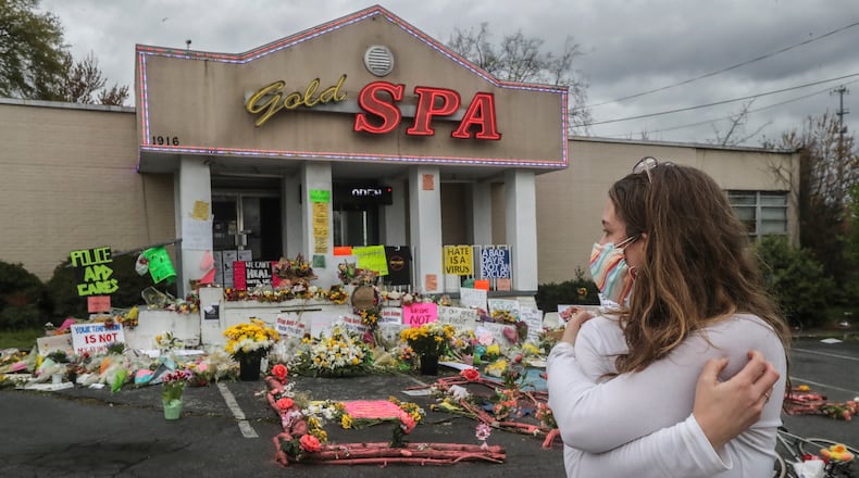 An emotional Hollis Wright gazes at the memorial-strewn front of the Gold Spa on Piedmont Avenue on Wednesday, March 24, 2021 in Atlanta. Wright regularly drives by the spa while taking her daughter to daycare. On this day she stopped to look at the flowers and read the notes left behind. The Gold Spa and the Aromatherapy Spa in Atlanta are two of the three spas where eight people were killed by a gunman on March 16, 2021. Six of the eight victims were Asian women. (John Spink / John.Spink@ajc.com)