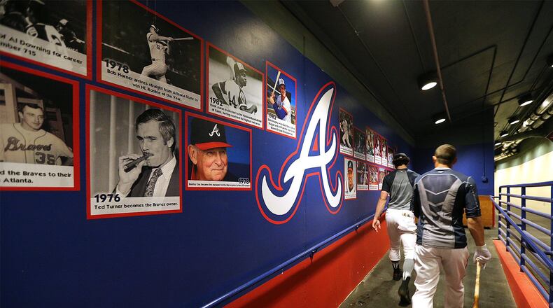 The Braves’ Dansby Swanson (left) and Jace Peterson make their way into the clubhouse past a wall of Braves history at spring training in Champion Stadium at the ESPN Wide World of Sports in Lake Buena Vista, Fla. (Curtis Compton/ccompton@ajc.com)