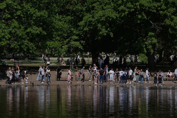People walk on a sunny day at a park in London, Wednesday, April 30, 2025. (AP Photo/Kin Cheung)