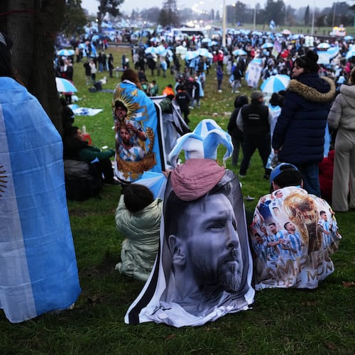 An Argentina fan wrapped in a flag bearing an image of Lionel Messi gathers outside the Argentine Football Association headquarters while waiting for the national team to arrive in Ezeiza, on the outskirts of Buenos Aires, Monday, July 20, 2026, following its World Cup final loss to Spain. (AP Photo/Rodrigo Abd)