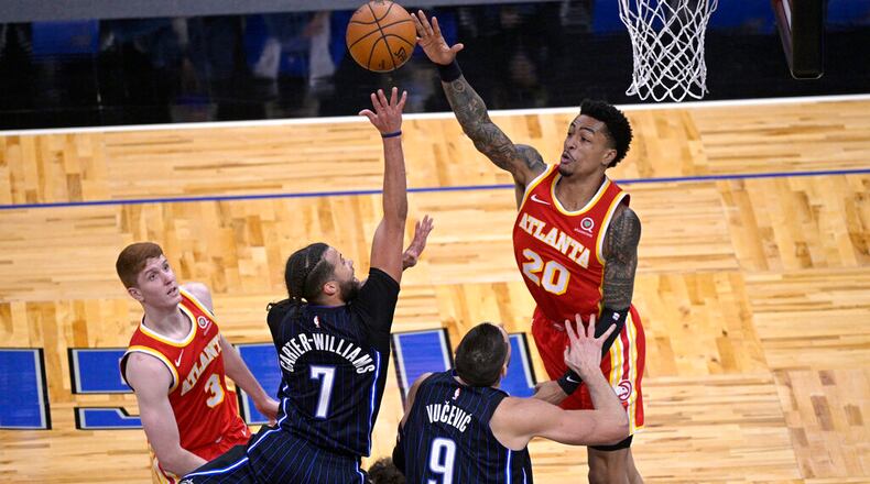 Orlando Magic guard Michael Carter-Williams (7) goes up for a shot between Atlanta Hawks guard Kevin Huerter (3) and forward John Collins (20) during the second half of an NBA basketball game Wednesday, March 3, 2021, in Orlando, Fla. (AP Photo/Phelan M. Ebenhack)