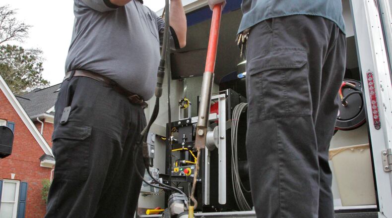 James Wright (left) and Chad Knock lower a Cues OZII remote controlled pipeline inspection camera into a Cherokee County sewer line for routine inspection. The Cherokee County Water and Sewerage Authority puts an emphasis on preventive maintenance and inspections. Sewer line camera crews inspect the pipes using remote controlled robotic cameras and coordinate with other departments for repairs when problems are found. The biggest issue is tree roots clogging the drains.