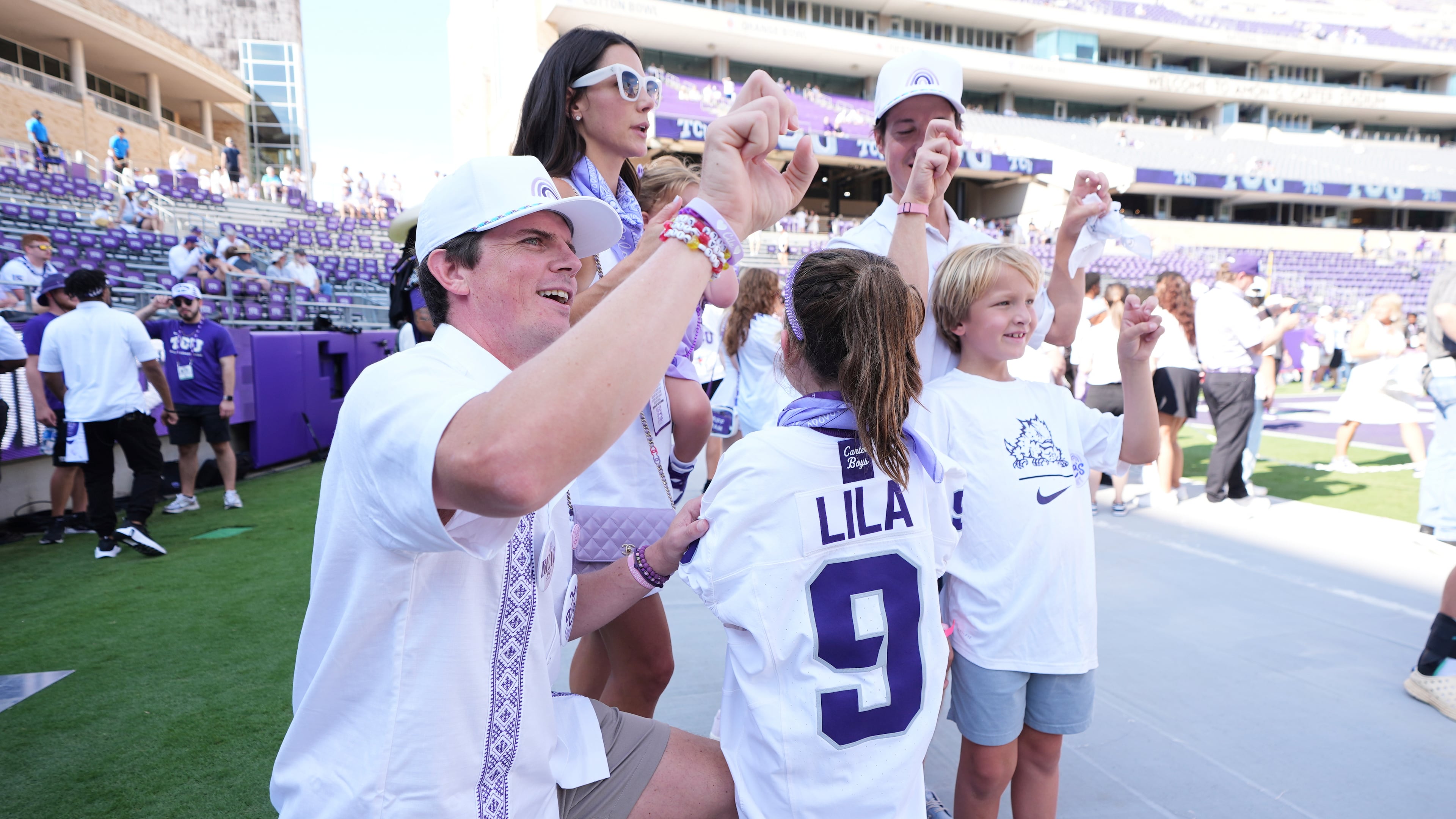 Blake Bonner, left, his wife Caitlin, left rear, standing and their daughter, front, wearing a shirt with her late sisters name stand in the end zone before an NCAA college football game between SMU and TCU, Saturday, Sept. 20, 2025, in Fort Worth, Texas. (AP Photo/Tony Gutierrez)