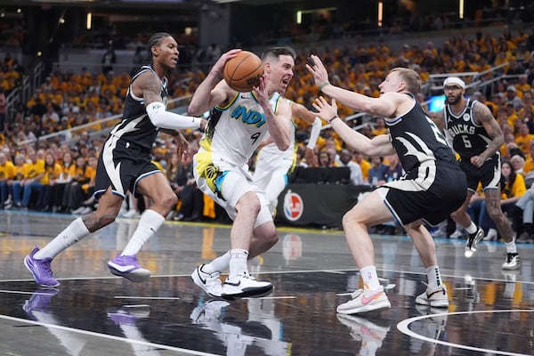 Indiana Pacers' T.J. McConnell (9) heads to the basket as Milwaukee Bucks' Kevin Porter Jr., left, and AJ Green, right, defend during the first half of a first-round NBA basketball playoff game, Saturday, April 19, 2025, in Indianapolis. (AP Photo/Michael Conroy)