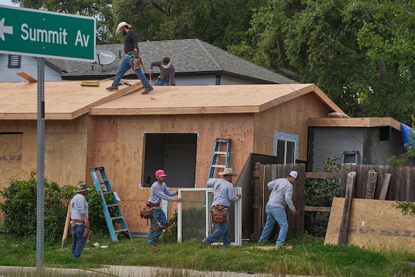 Construction crews build a new roof and windows on a fire damaged home in Altadena, Calif., on Friday, April 4, 2025. (AP Photo/Damian Dovarganes)