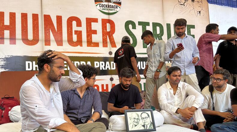 Abhijeet Dipke, founder of the Cockroach Janta Party, center sitting, starts his indefinite hunger strike during a protest demanding the resignation of Education Minister Dharmendra Pradhan over alleged examination irregularities and repeated paper leaks in New Delhi, India, Saturday, July 18, 2026. (AP Photo/Shonal Ganguly)