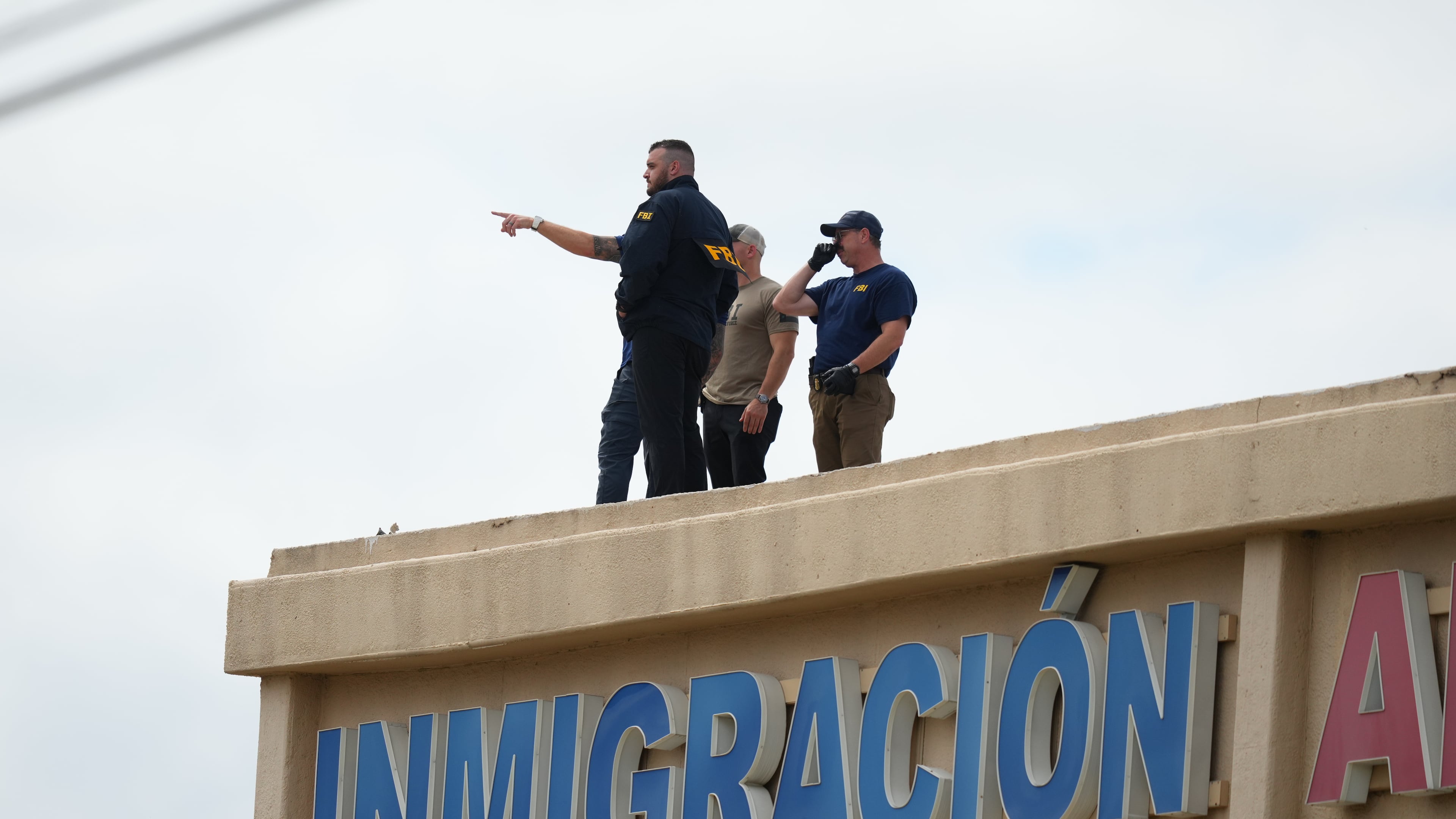 Law enforcement agents look around the roof of a building near the scene of a shooting at a U.S. Immigration and Customs Enforcement office in Dallas on Wednesday, Sept. 24, 2025. (AP Photo/Julio Cortez)