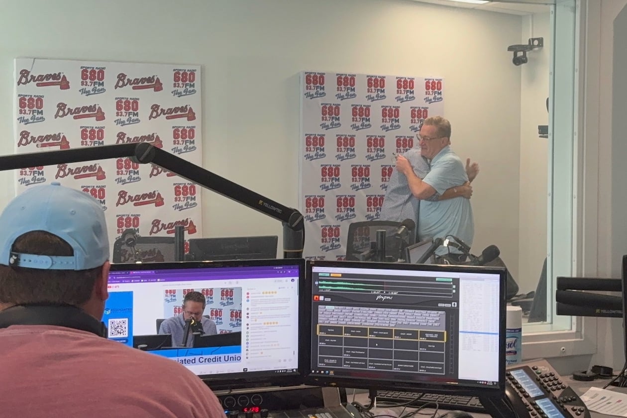 Moments after the final episode of the "Chuck and Chernoff" show on 93.7/680 The Fan wrapped up on Aug. 18, show hosts Chuck Oliver (right) and Matt Chernoff share a hug. Show producer Cullen Madden is in the foreground. (Ken Sugiura/AJC)