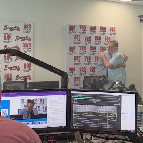 Moments after the final episode of the "Chuck and Chernoff" show on 93.7/680 The Fan wrapped up on Aug. 18, show hosts Chuck Oliver (right) and Matt Chernoff share a hug. Show producer Cullen Madden is in the foreground. (Ken Sugiura/AJC)