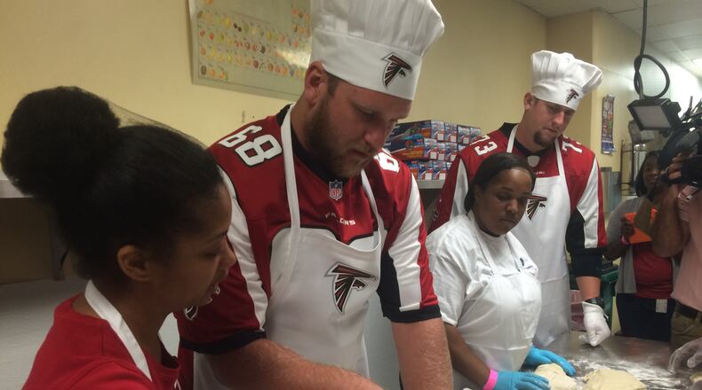 Atlanta Falcons players Mike Peterson (center) and Ryan Schraeder work with Westside Works culinary students to prepare challah bread.